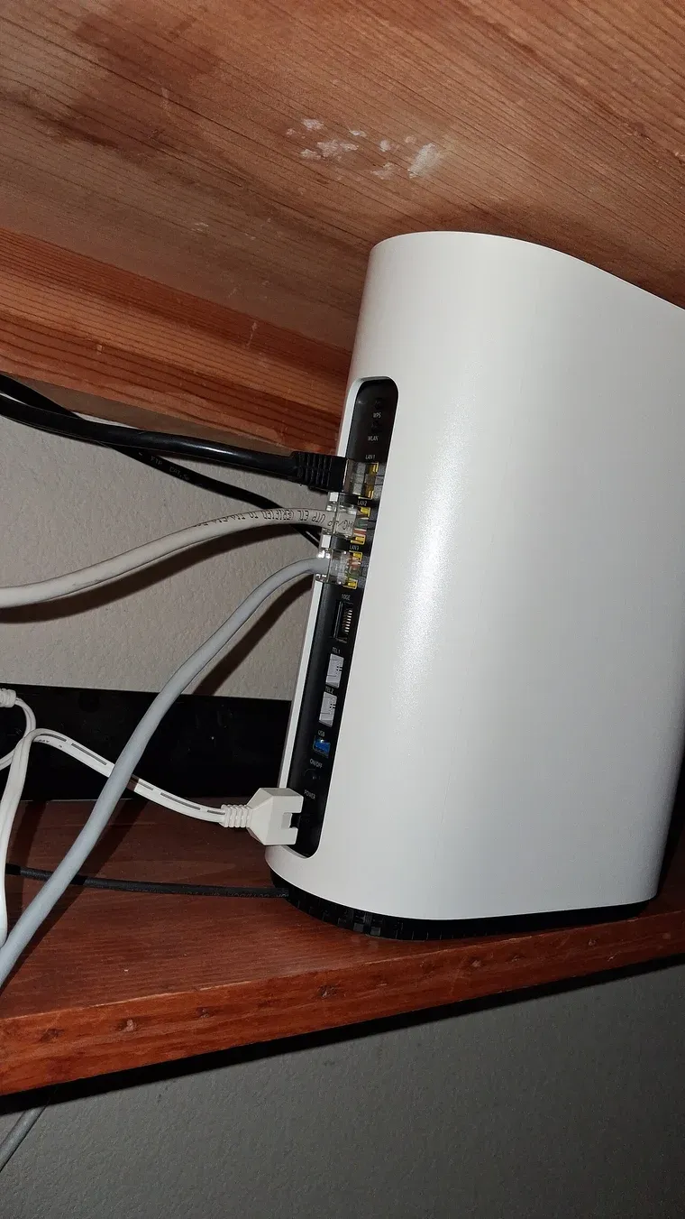 ظهر جهاز مزود ألياف أبيض طويل من Nokia على رف خشبي، فيه ثلاثة منافذ LAN موصول بها كابلات Ethernet، ومنفذ 10GE، ومنفذا هاتف TEL 1 وTEL 2، ومنفذ USB وزر التشغيل والكهرباء