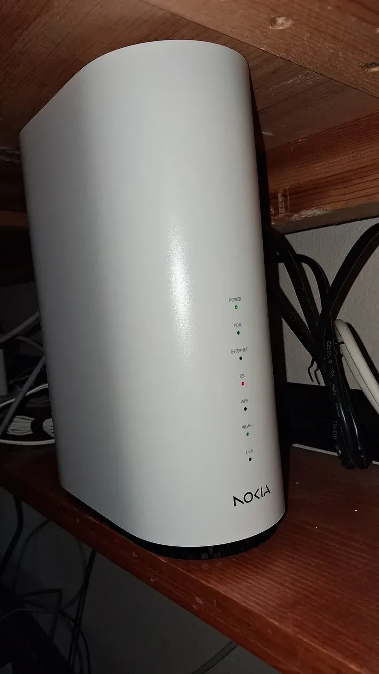 جهاز Nokia أبيض طويل على رف خشبي يجمع ONT للألياف وRouter بشبكة Wi-Fi 6، وفي واجهته أضواء حالة منها PON والإنترنت وWi-Fi