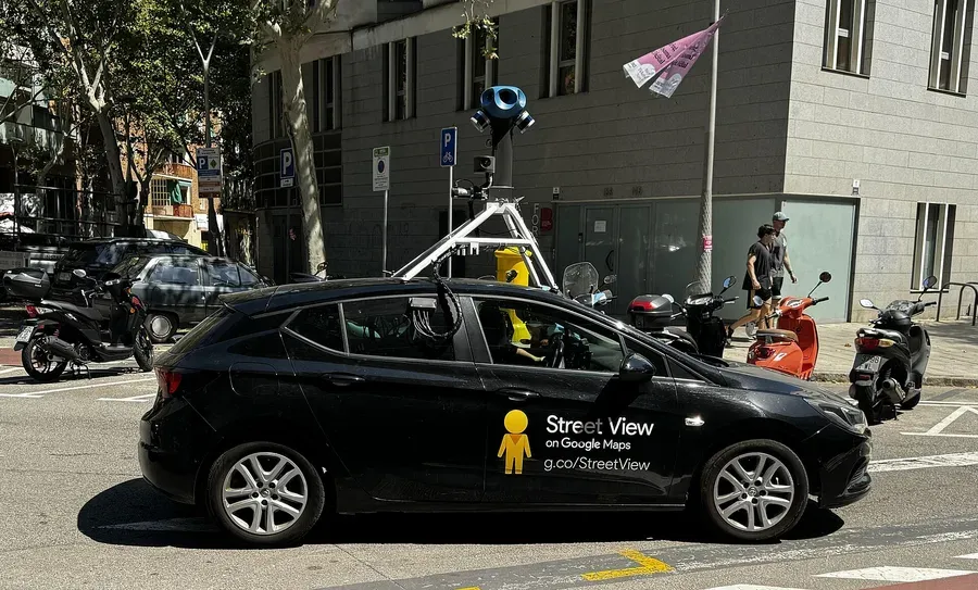 سيارة سوداء صغيرة في شارع في برشلونة عليها شعار Street View on Google Maps، وفوق سقفها هيكل أبيض يحمل عموداً في أعلاه رأس أزرق مستدير عليه عدسات